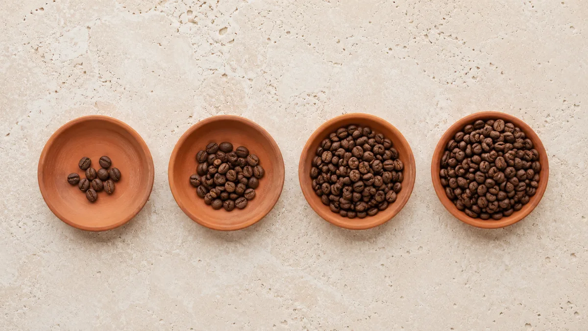 Four terracotta dishes holding increasing quantities of coffee beans