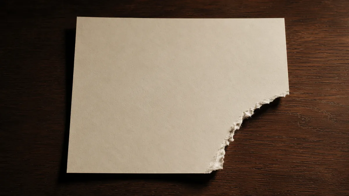 A sheet of cream paper with one corner torn away