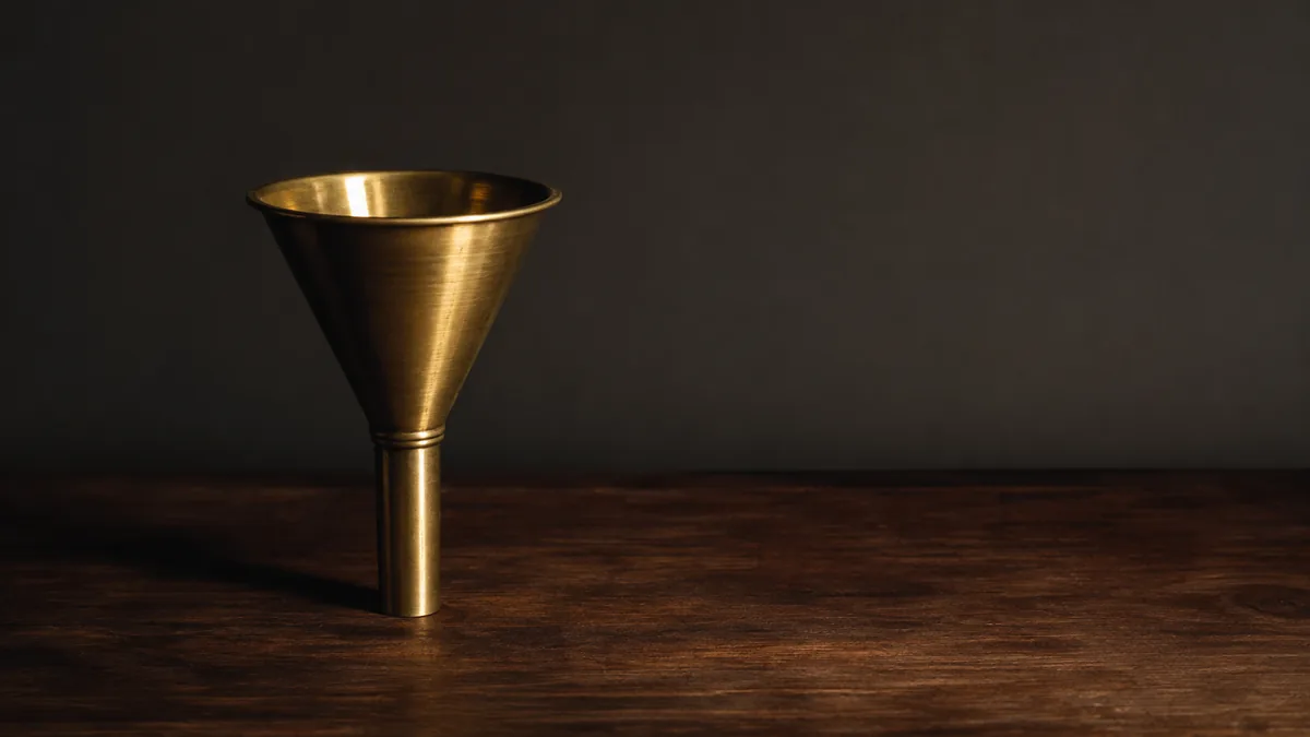 An upright brass funnel on a dark walnut surface