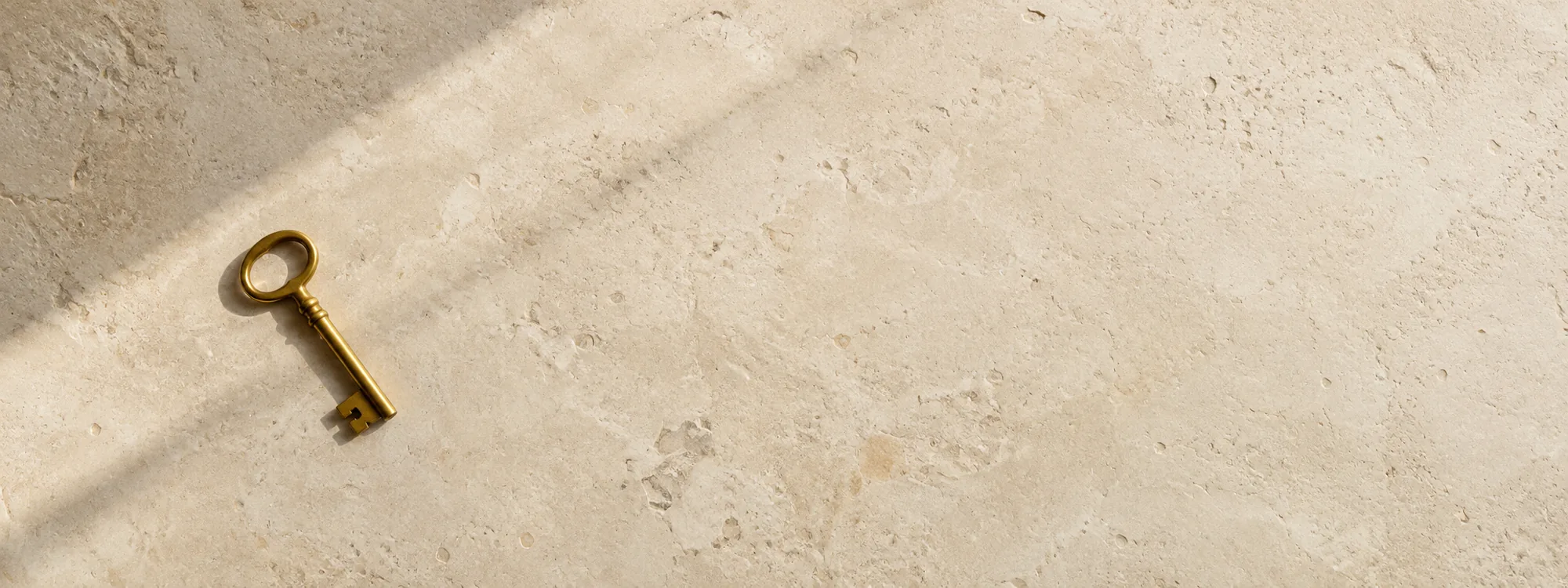 A brass key on a pale limestone surface